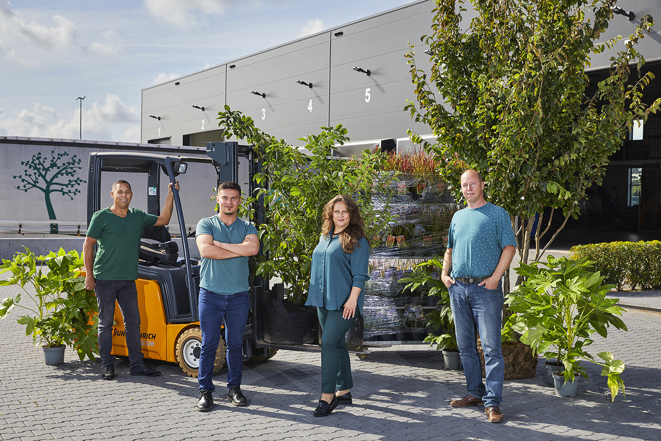 Agro-NL Consult Solutions team with ornamental plants ready for export, standing by a forklift at a modern warehouse.