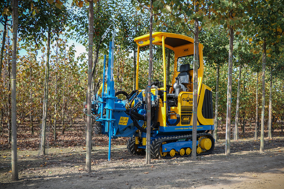 Agricultural machinery operating in a plant nursery, surrounded by rows of trees, representing Agro-NL Consult Solutions` services.